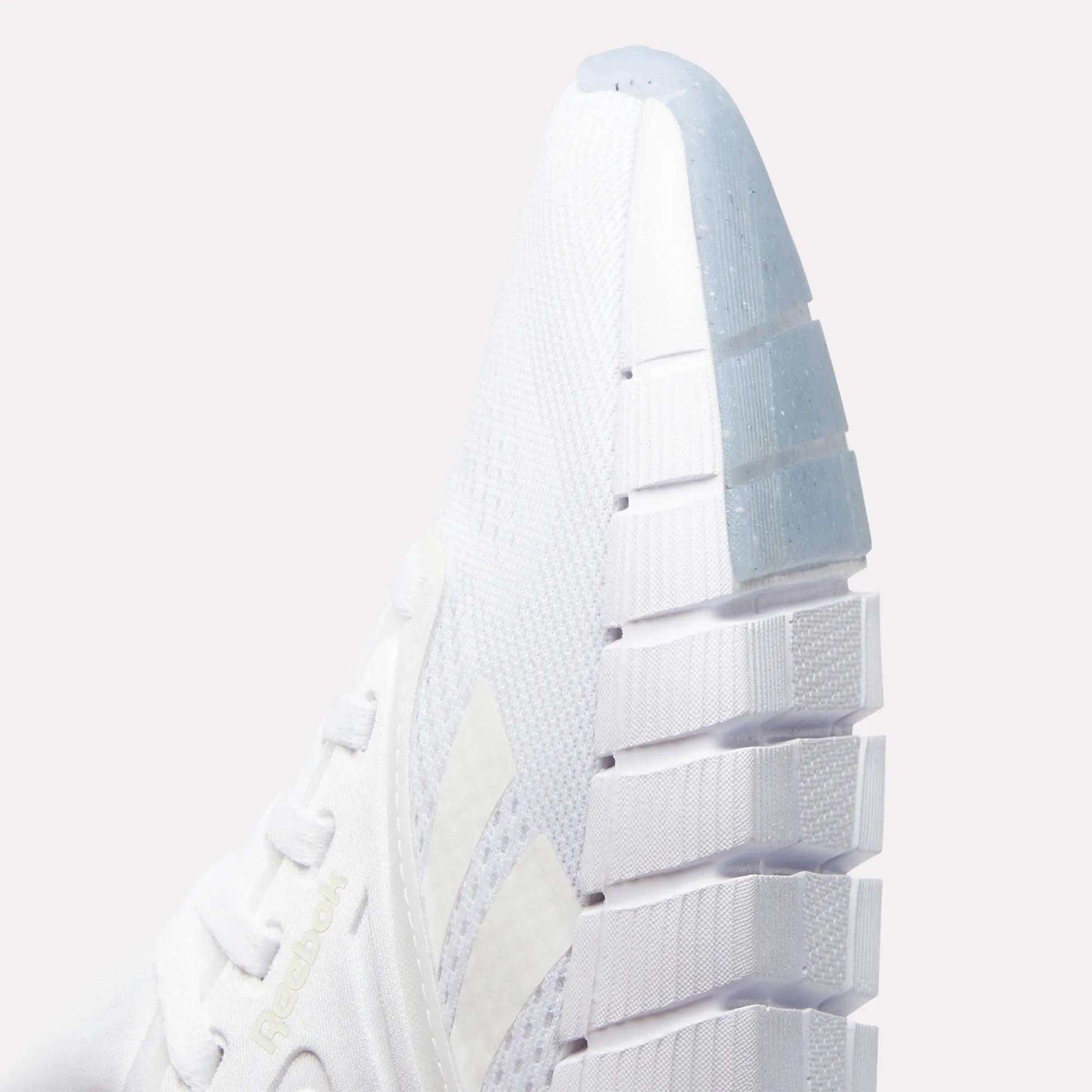 Close-up of the front and side of a white Reebok Women's Nano Gym Training Shoe featuring textured mesh fabric, white laces, a thick grooved sole, and the Reebok logo subtly displayed on the side.
