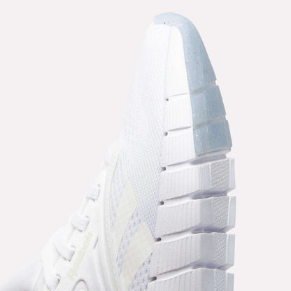 Close-up of the front and side of a white Reebok Women's Nano Gym Training Shoe featuring textured mesh fabric, white laces, a thick grooved sole, and the Reebok logo subtly displayed on the side.