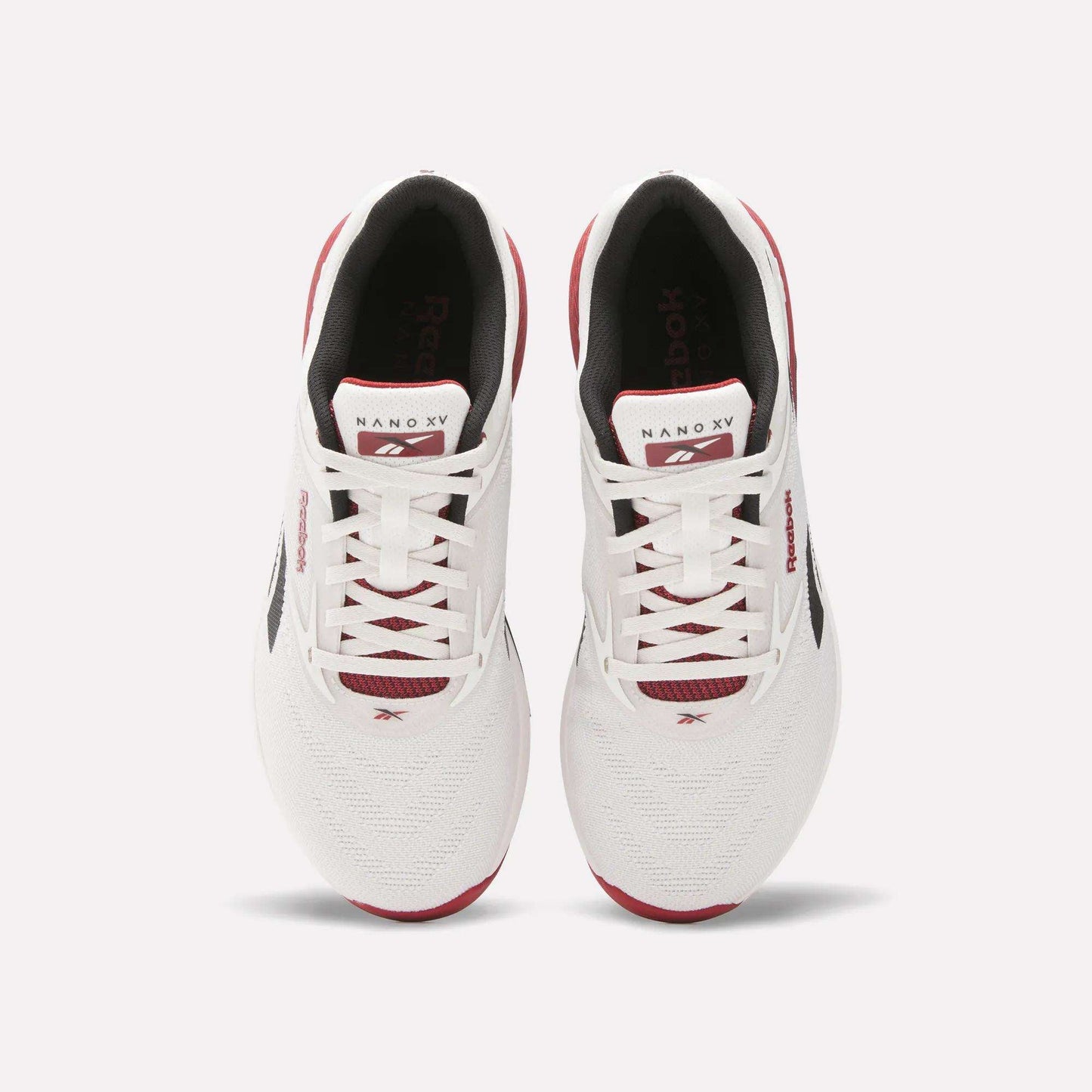 A pair of white Reebok Nano X5 training shoes with red and black accents, viewed from above, featuring laces, branded tongue, and mesh toe boxes against a light background. Perfect men’s workout shoes from Reebok.