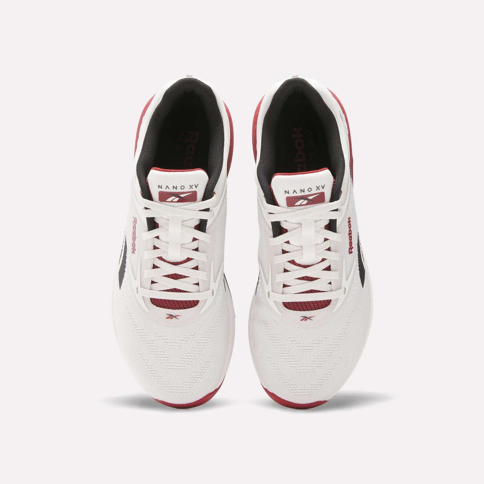 A pair of white Reebok Nano X5 training shoes with red and black accents, viewed from above, featuring laces, branded tongue, and mesh toe boxes against a light background. Perfect men’s workout shoes from Reebok.