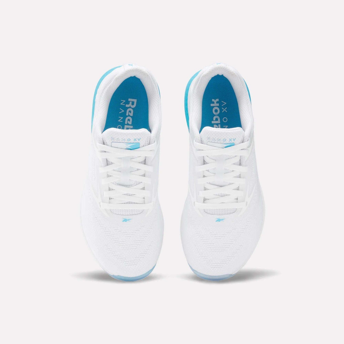 Top view of Reebok Women's Nano X5 Training Shoes in white, with blue insoles and soles, white laces, and subtle blue accents. Shoes are placed side by side on a light background.