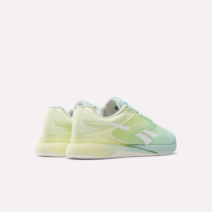 The Reebok Women's Nano X5 Training Shoes in pastel green and yellow feature white soles and signature stripes, shown from an angled rear view on a plain white background.