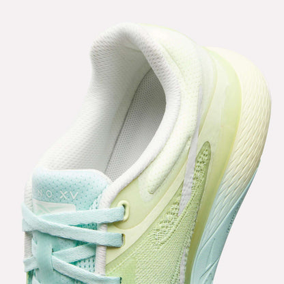 A close-up of the Reebok Women's Nano X5 Training Shoes shows pastel light green and aqua hues, white laces, a textured sole, and a padded collar for comfort. The inner lining and tongue are white.