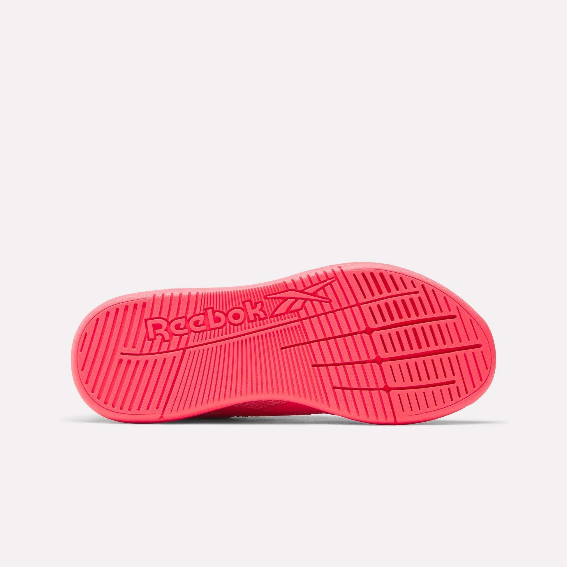 The image displays the bright pink sole of the Reebok Women's Nano X5 Training Shoes, viewed from below. The center features an embossed Reebok logo, and the textured pattern on the sole provides grip.