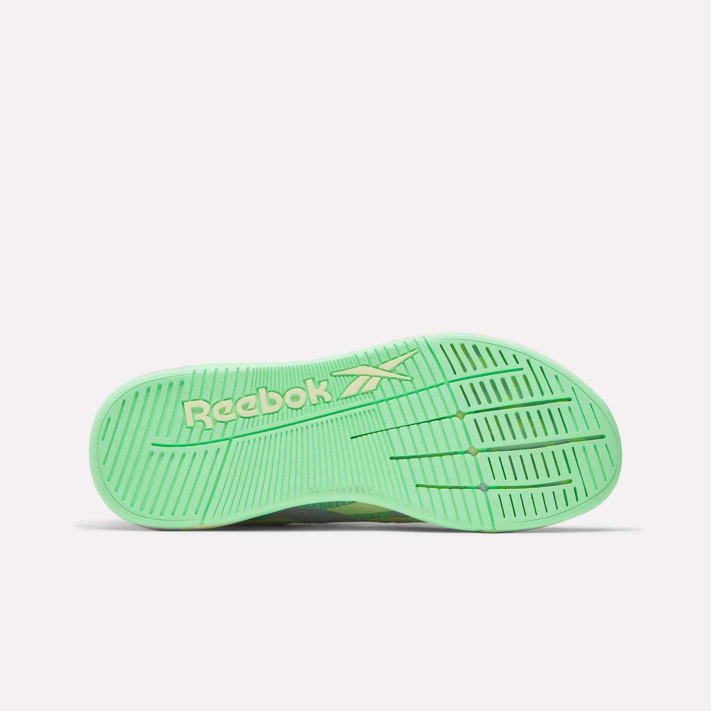 The image displays the bottom view of a green Women's Nano X5 Training Shoe by Reebok, showing a white Reebok logo and textured sole grooves for grip—an iconic addition to women’s training shoe collections.