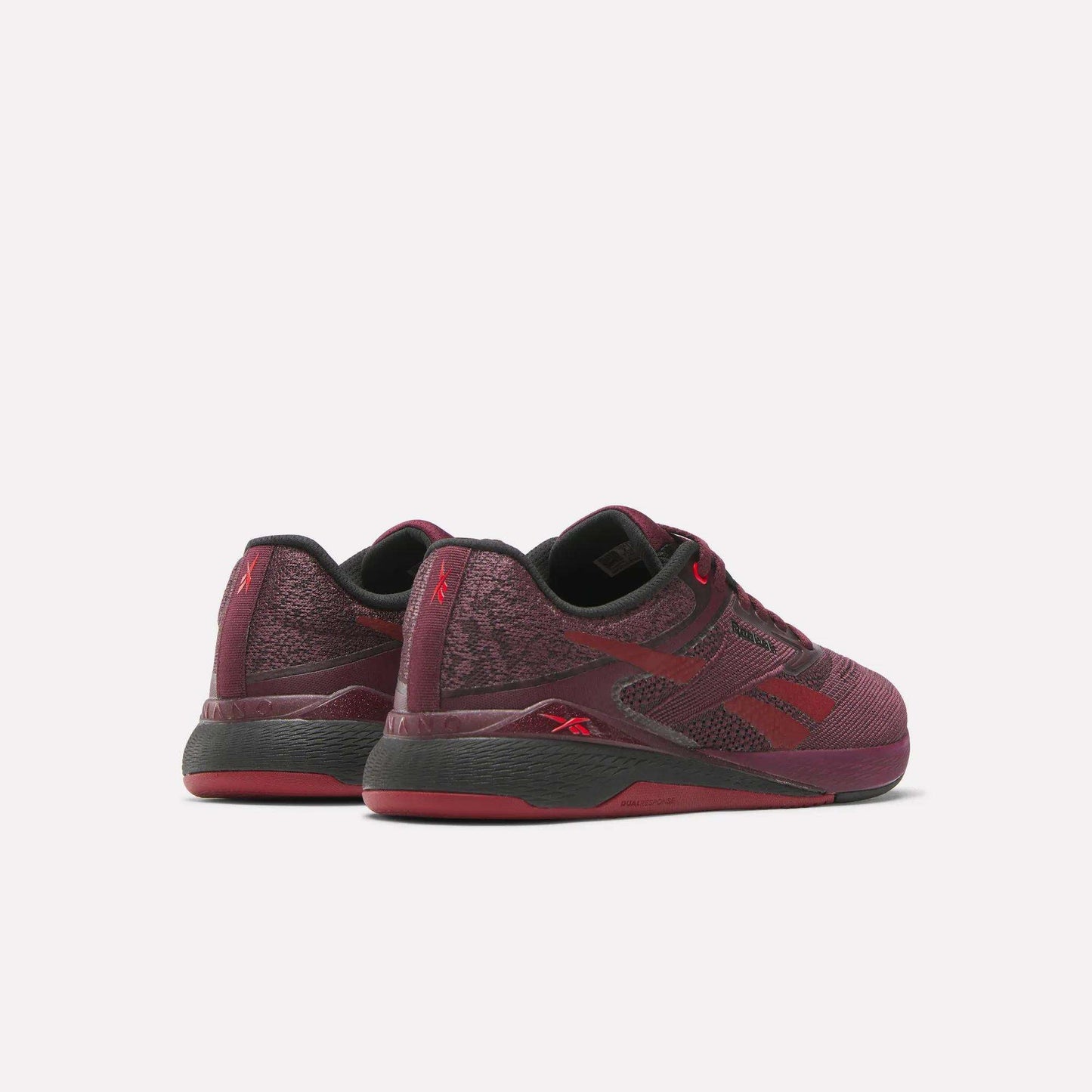 The Reebok Women's Nano X5 Training Shoes in maroon with black and red accents are designed for comfort, shown from the back and side against a plain white background.