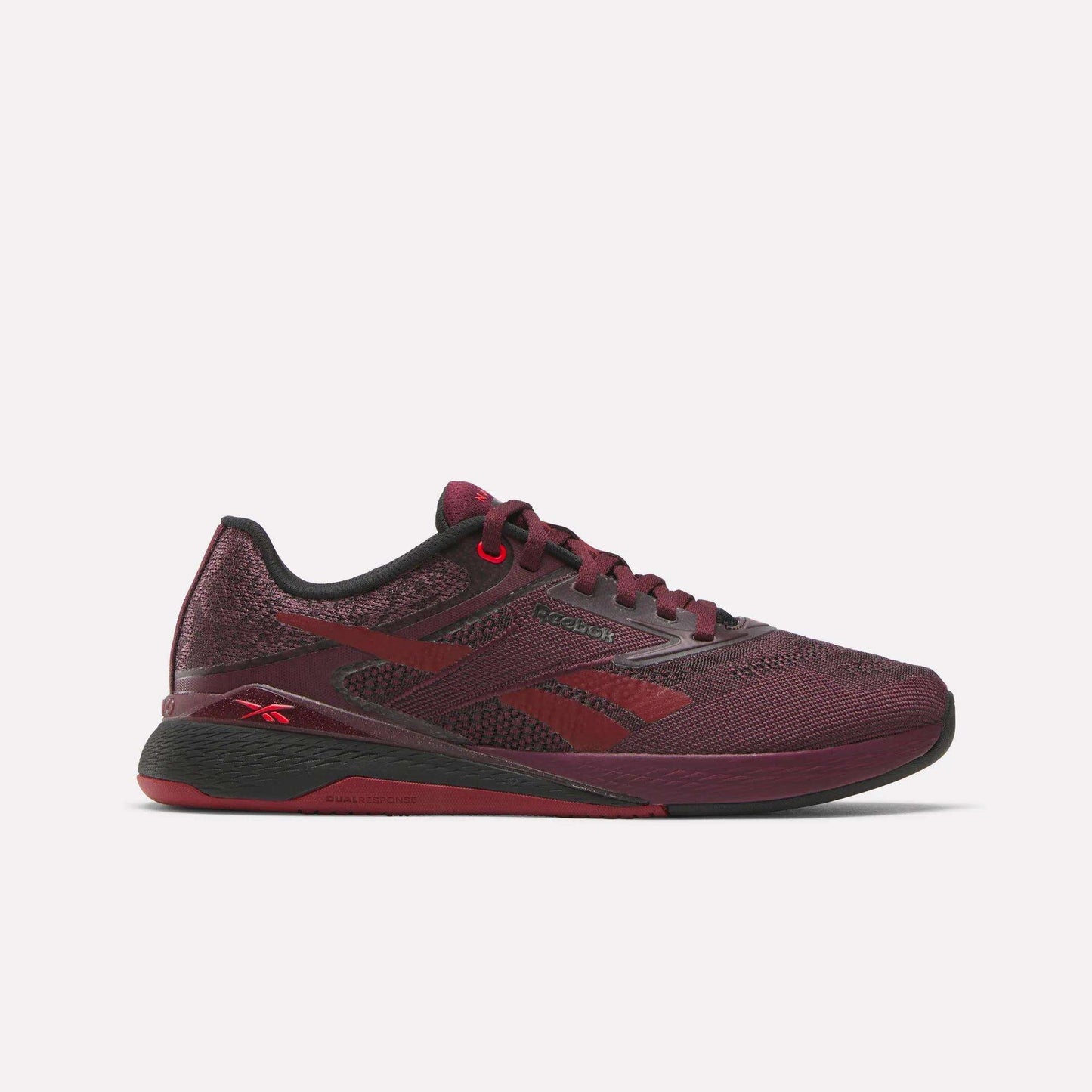 The Women's Nano X5 Training Shoes by Reebok feature a maroon mesh upper with black accents, a red Reebok logo on the heel, textured sole, and are displayed against a plain white background.