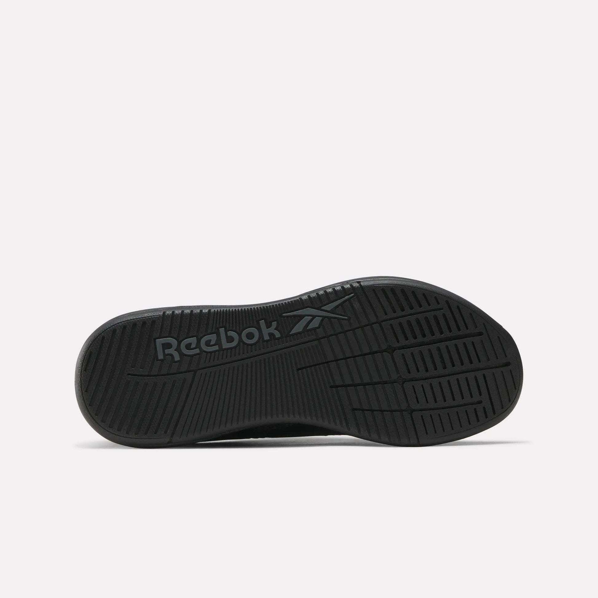 The image displays the black sole of the Reebok Women's Nano X5 Training Shoes, featuring the Reebok name and logo embossed at the center. Grooves and textured patterns provide grip, shown against a plain white background.