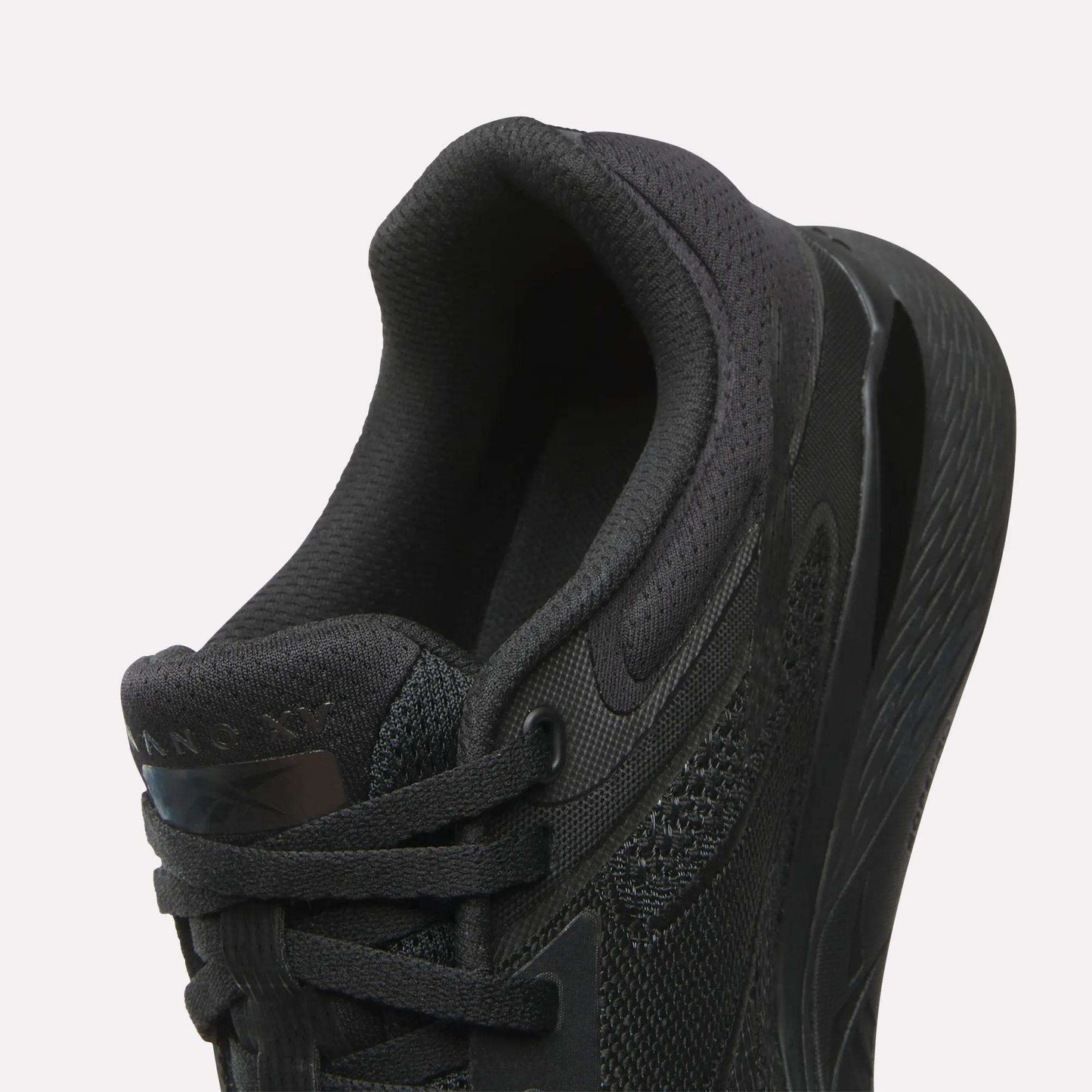 Close-up of the Reebok Women's Nano X5 Training Shoe in black, highlighting its heel, padded collar, laces, and textured midsole against a white background—ideal for women’s shoe collections.
