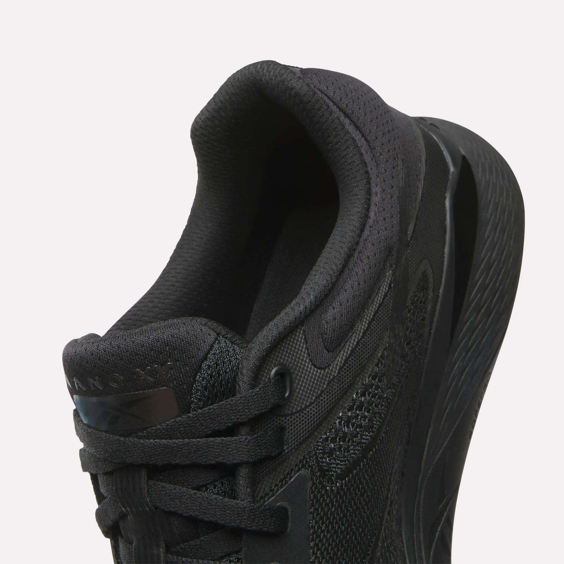 Close-up of the Reebok Women's Nano X5 Training Shoe in black, highlighting its heel, padded collar, laces, and textured midsole against a white background—ideal for women’s shoe collections.