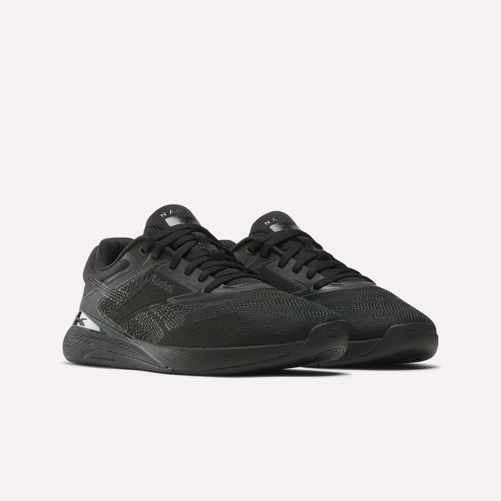 A pair of Women's Nano X5 Training Shoes by Reebok in black, featuring mesh uppers and textured details, displayed at an angle on a light background.