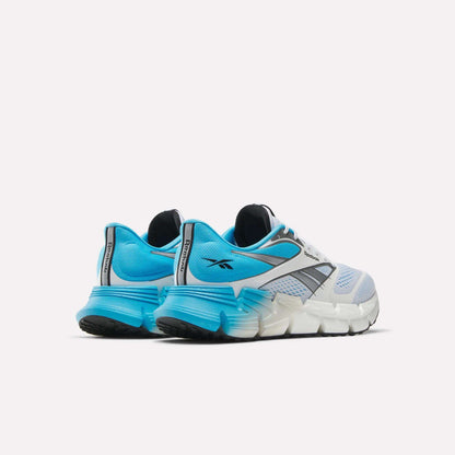 The Reebok Men's FloatZig 2 Running Shoes in blue, white, and black feature thick Superfloat+ cushioned soles for energy-returning comfort, breathable mesh uppers, and Reebok logos on the heel and side.
