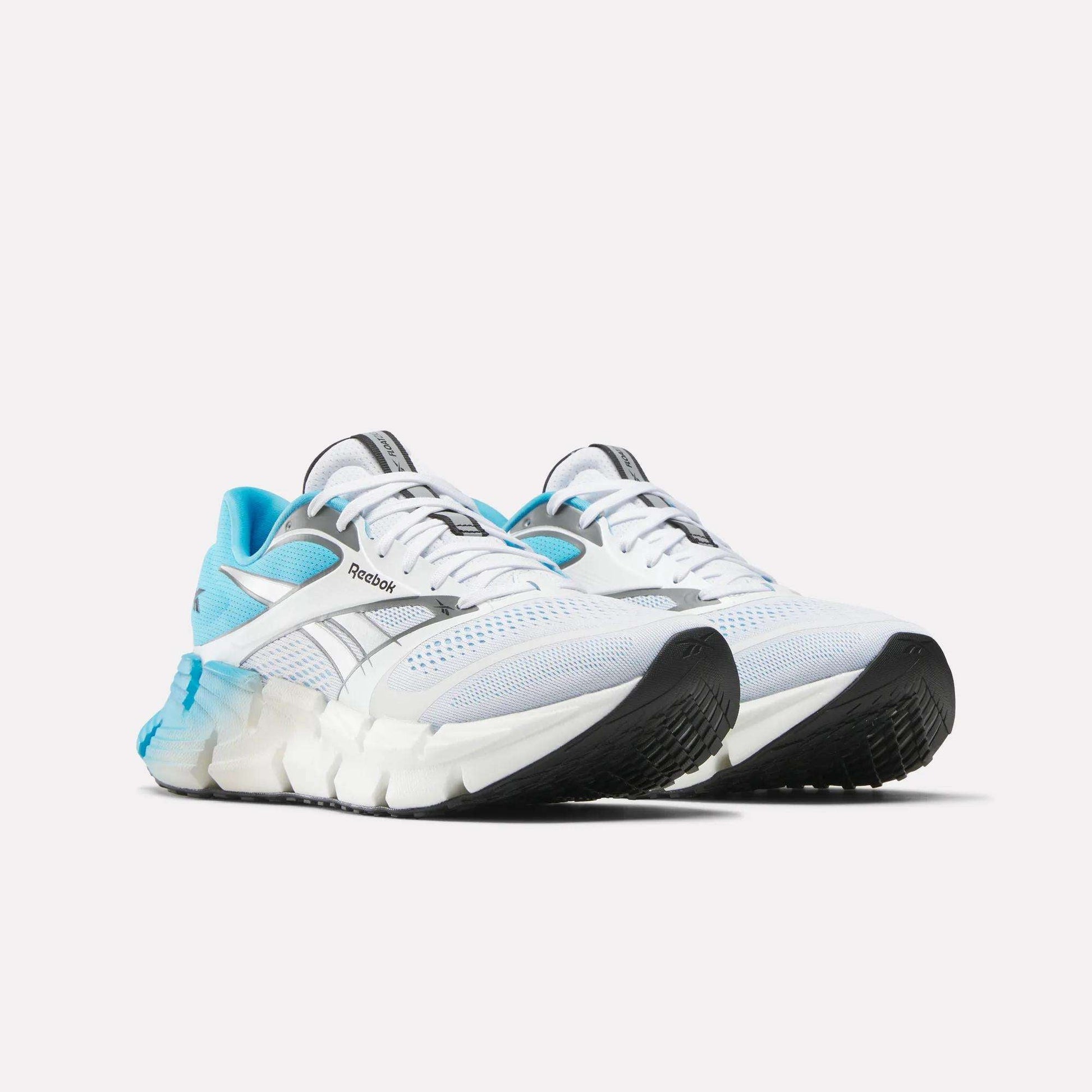 The Reebok Men's FloatZig 2 Running Shoes in white with light blue accents, black soles, and mesh details are shown on a plain white background, featuring Superfloat+ cushioning for enhanced comfort.
