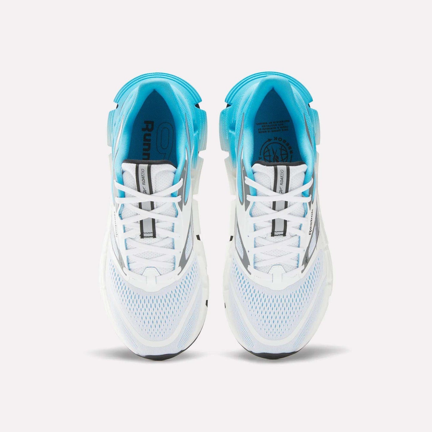 Top view of Reebok Men's FloatZig 2 Running Shoes with white mesh uppers, light blue accents, Superfloat+ cushioning, and black sole details—arranged side by side on a plain white background.
