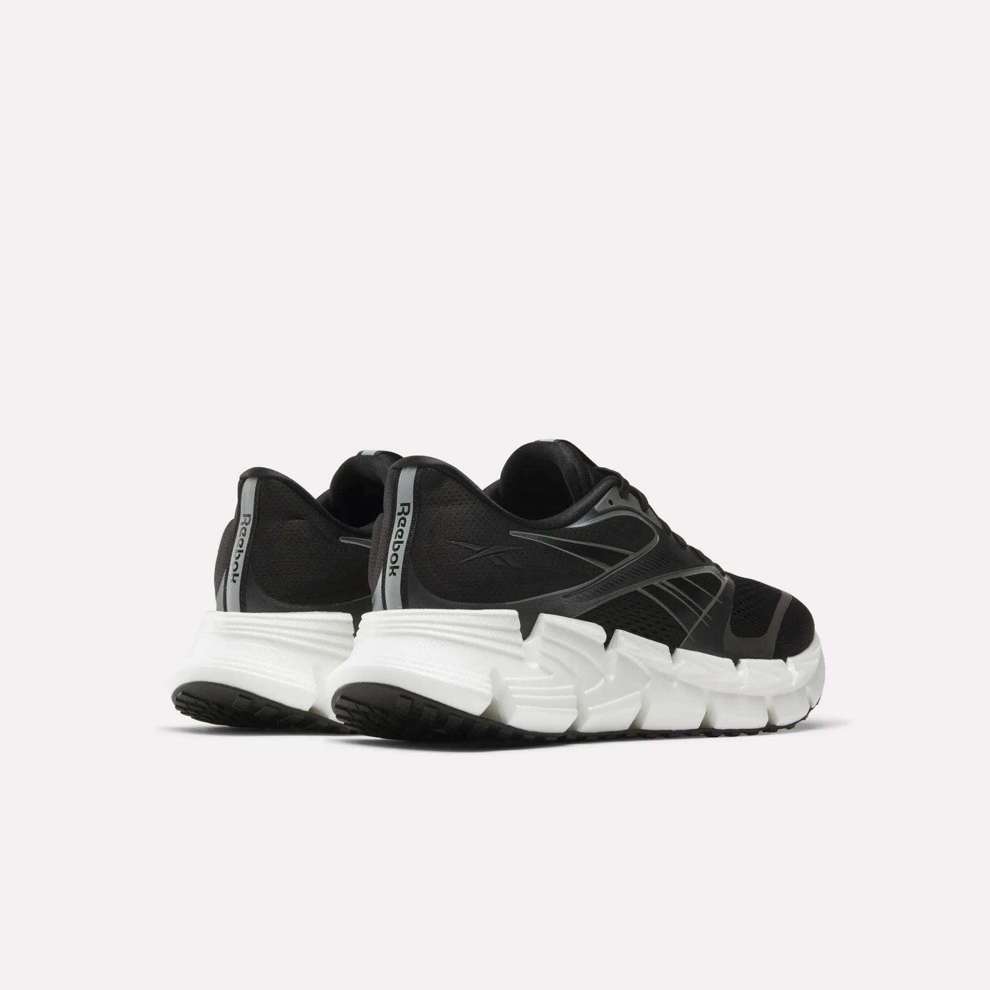 The men's Reebok FloatZig 2 running shoes in black feature chunky white soles and Superfloat+ cushioning, displayed from back and side angles against a plain light background.