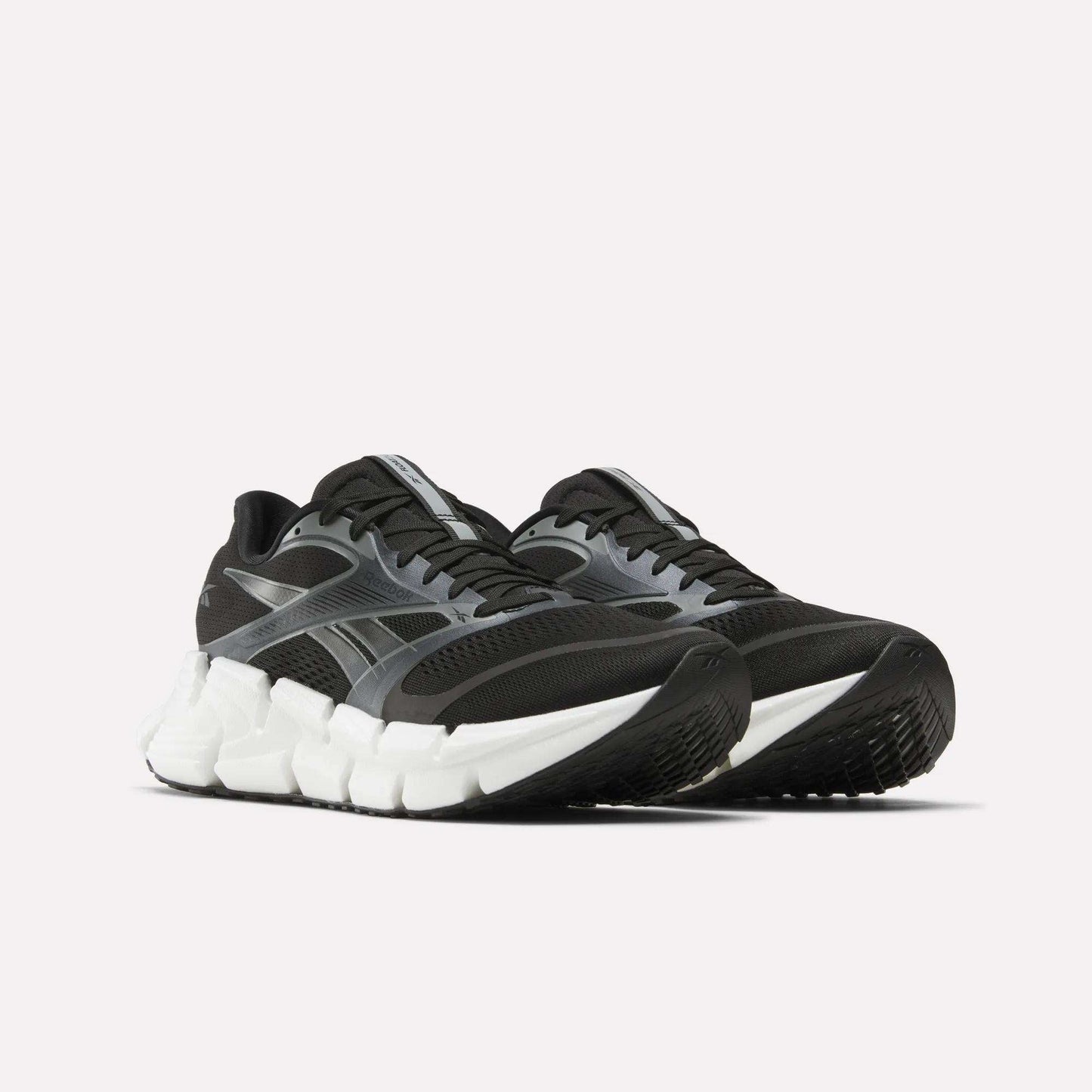 A pair of Reebok Men's FloatZig 2 Running Shoes in black and gray with thick white Superfloat+ cushioned soles, shown from a low front angle against a plain light background.
