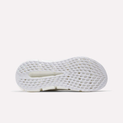 The image shows the bottom view of a white Reebok Men's FloatZig 2 Running Shoe sole with grid-like textured grooves, a central cutout for traction and flexibility, and energy-returning cushioning on a light gray background.