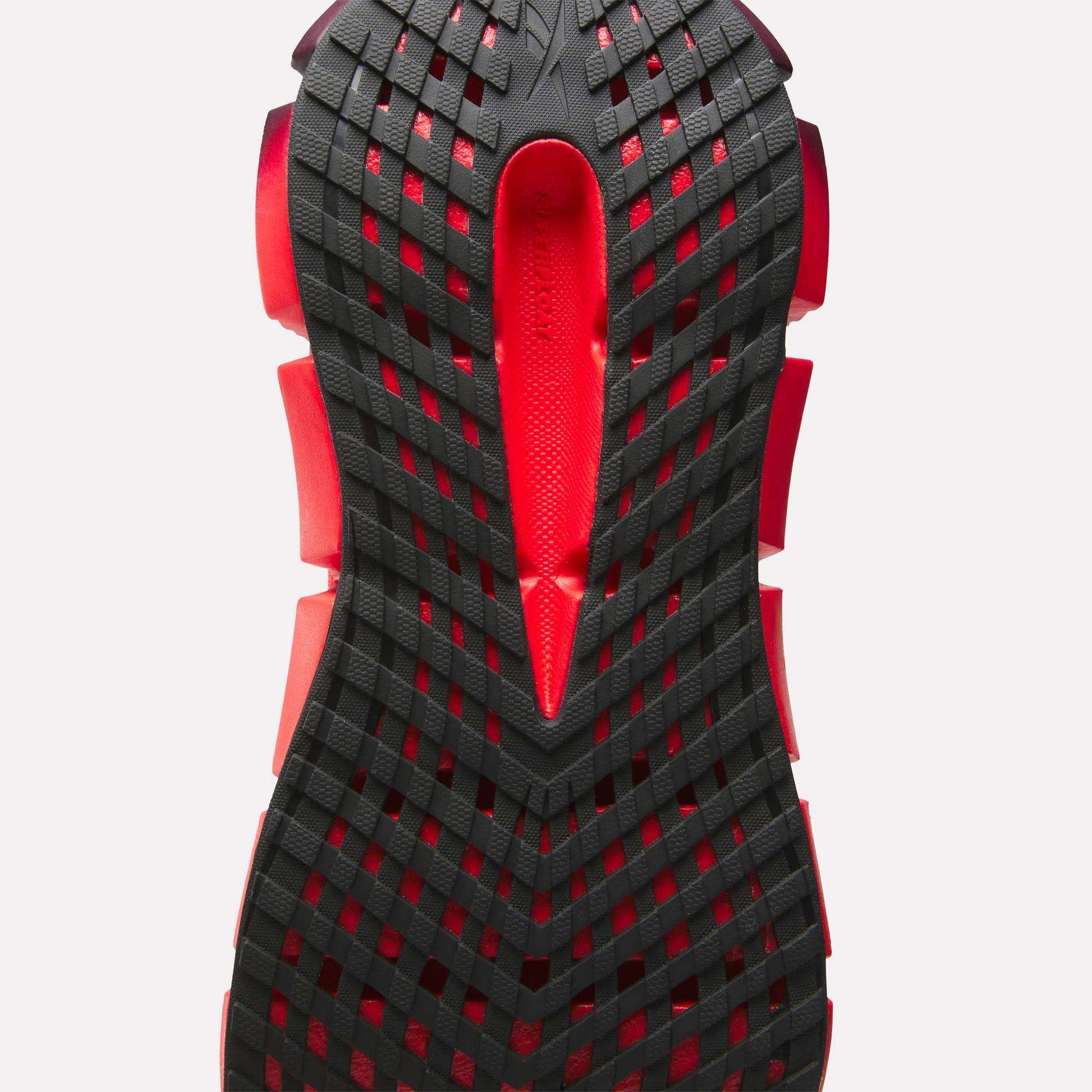 Close-up of the Reebok Women's FloatZig 2 Running Shoe sole, showing a black grid pattern with red accents, Superfloat+ cushioning, and a central cutout, set against a light background.