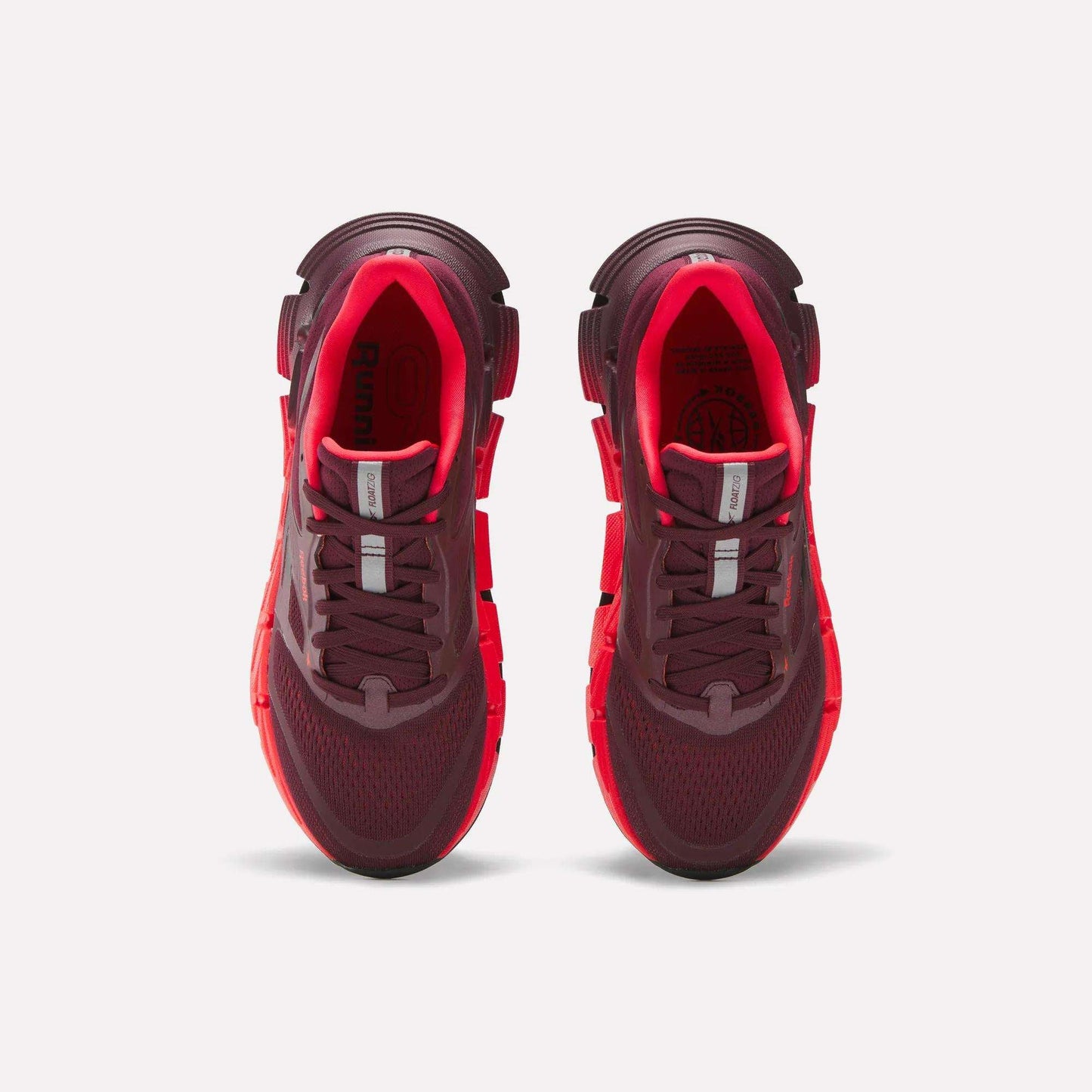A pair of maroon and bright red Reebok Women's FloatZig 2 Running Shoes is shown from above on a white background, highlighting the mesh uppers, laces, and cushioned soles with Superfloat+ technology.