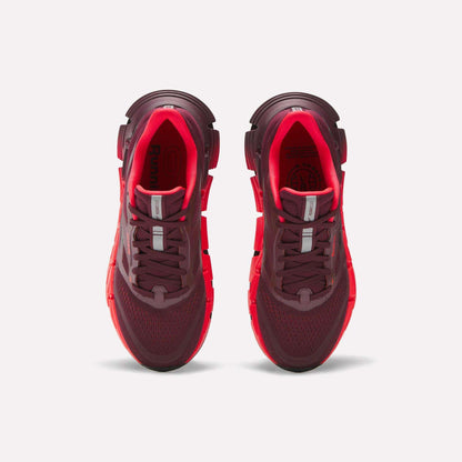 A pair of maroon and bright red Reebok Women's FloatZig 2 Running Shoes is shown from above on a white background, highlighting the mesh uppers, laces, and cushioned soles with Superfloat+ technology.