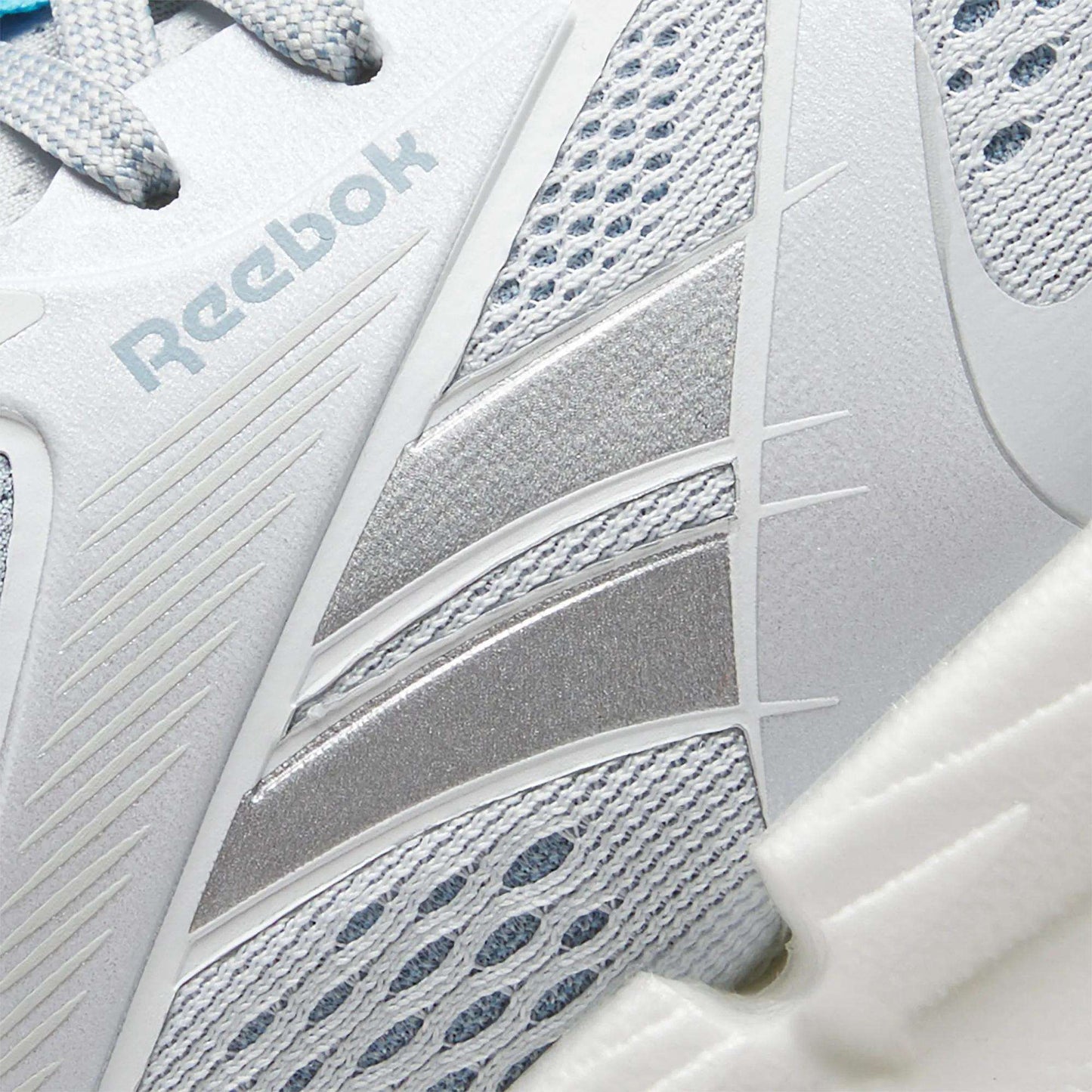 Close-up of Reebok Women's FloatZig 2 Running Shoes in white and silver, showing mesh and synthetic upper, detailed stitching, side Reebok logo, and a carbon rubber outsole for lasting traction.
