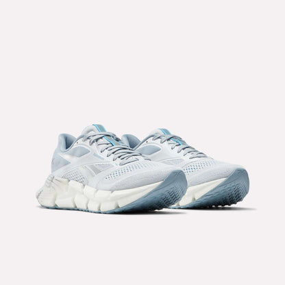 The Reebok Women's FloatZig 2 Running Shoes feature light blue and white mesh uppers, chunky soles with Superfloat+ cushioning, and carbon rubber textured outsoles, shown on a white background.