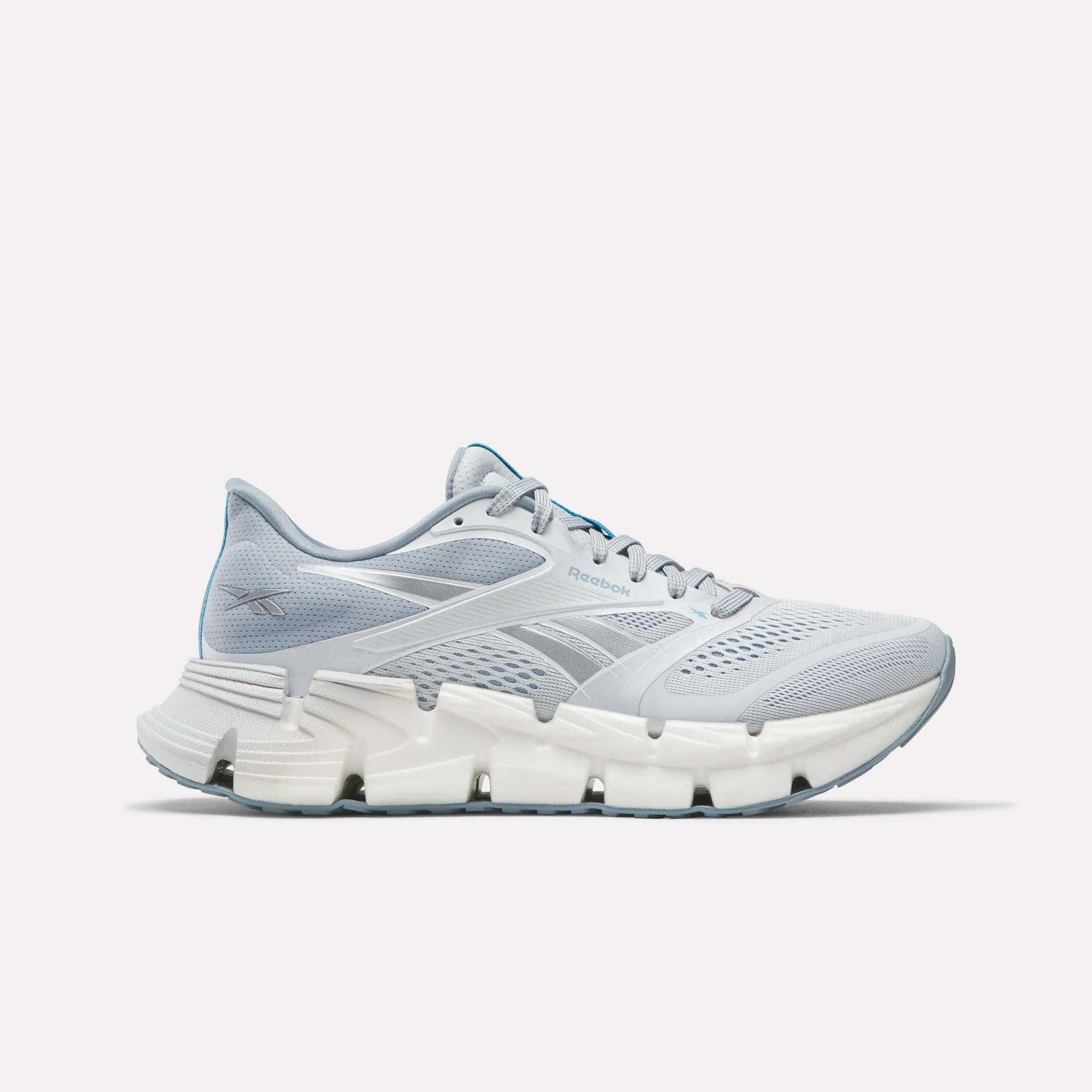 The Women's FloatZig 2 Running Shoes by Reebok feature a light gray mesh upper, white midsole with Superfloat+ cushioning, and a light blue carbon rubber outsole, shown against a plain white background.