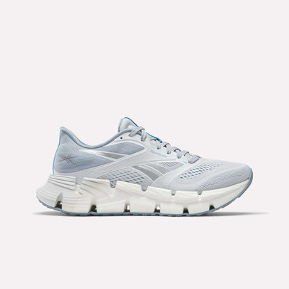 The Women's FloatZig 2 Running Shoes by Reebok feature a light gray mesh upper, white midsole with Superfloat+ cushioning, and a light blue carbon rubber outsole, shown against a plain white background.