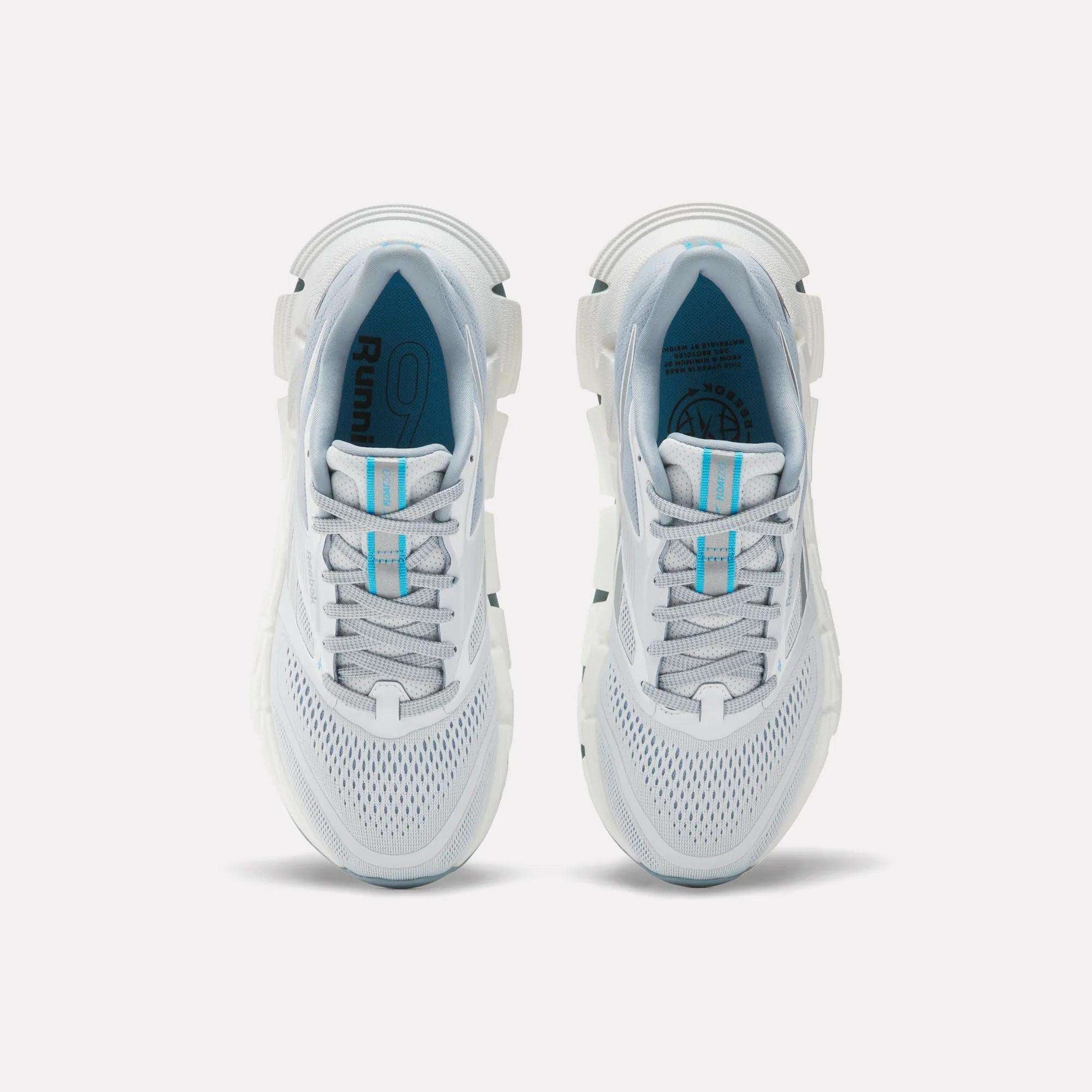 A pair of Women's FloatZig 2 Running Shoes by Reebok with white mesh uppers, light blue accents, gray details, Superfloat+ cushioning, and carbon rubber soles is shown from above on a plain white background.
