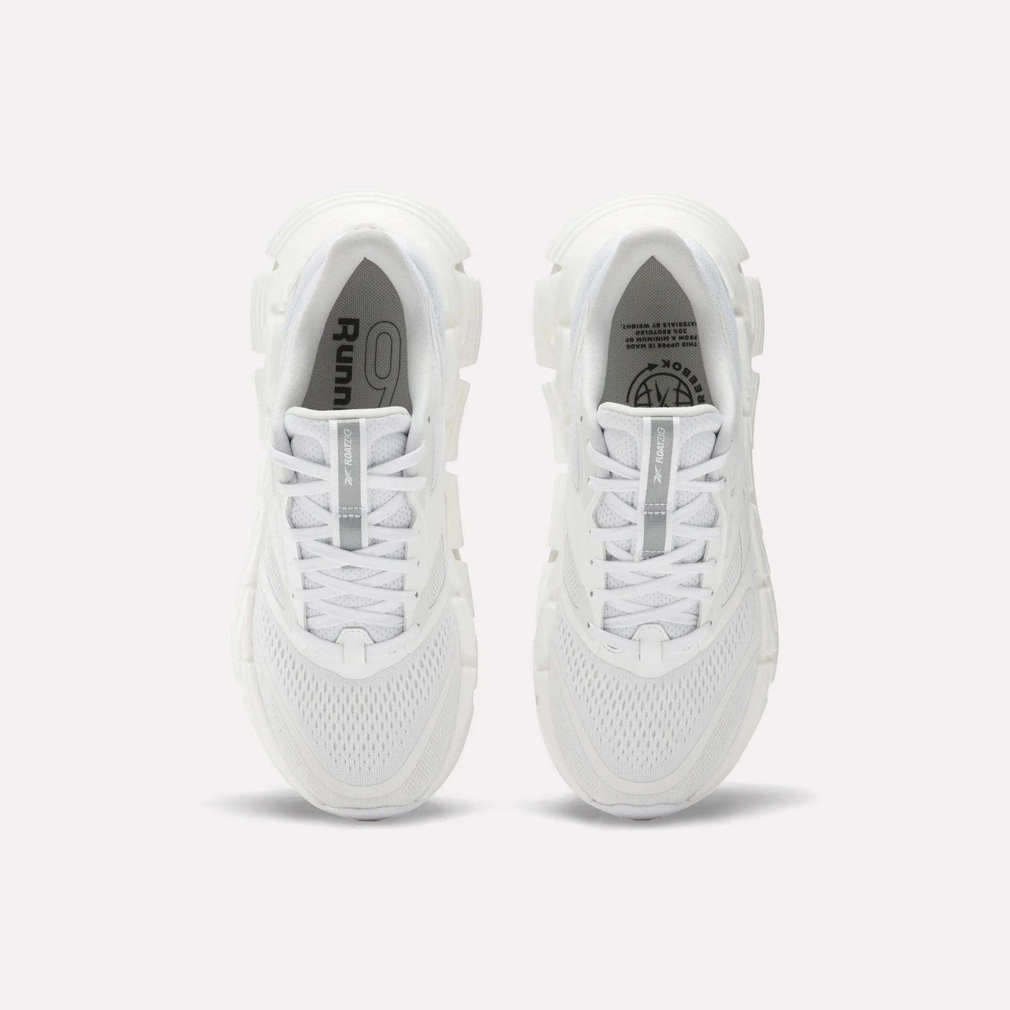 A pair of Women's FloatZig 2 Running Shoes by Reebok viewed from above, featuring white mesh uppers, chunky Superfloat+ cushioned soles, and white laces. The insoles show Reebok branding and graphic details.