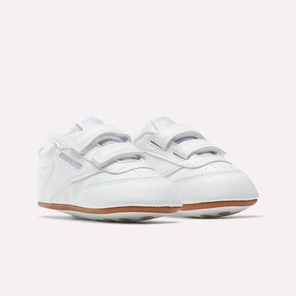 Reebok Kids' Club C Crib Shoes for babies and toddlers feature a soft white leather upper, hook-and-loop closures, and light brown rubber soles, displayed on a plain white background.