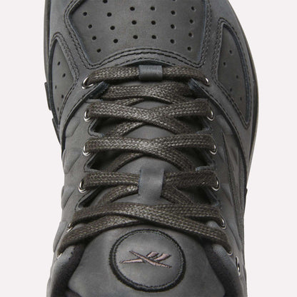 Close-up of the Reebok Nano 2.0 Training Shoes in black, featuring pebbled leather, laces, a perforated tongue, and stitched logo near the toe. Matte finish and detailed stitching around the laces enhance its premium look.