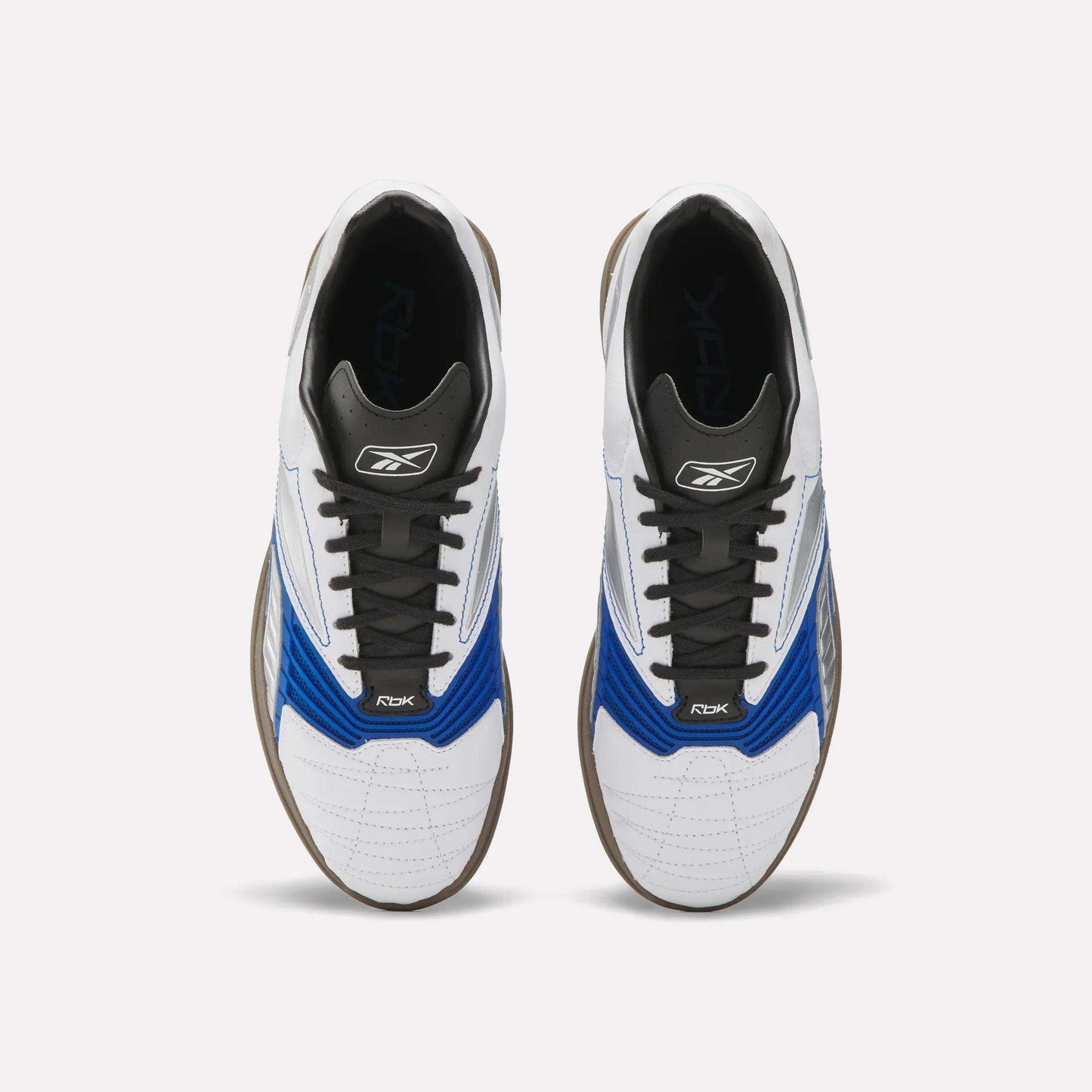 A pair of Reebok Hammer Valde Shoes seen from above, with a white leather upper, blue and black accents, black laces, brown soles, and branding on the tongue and side.