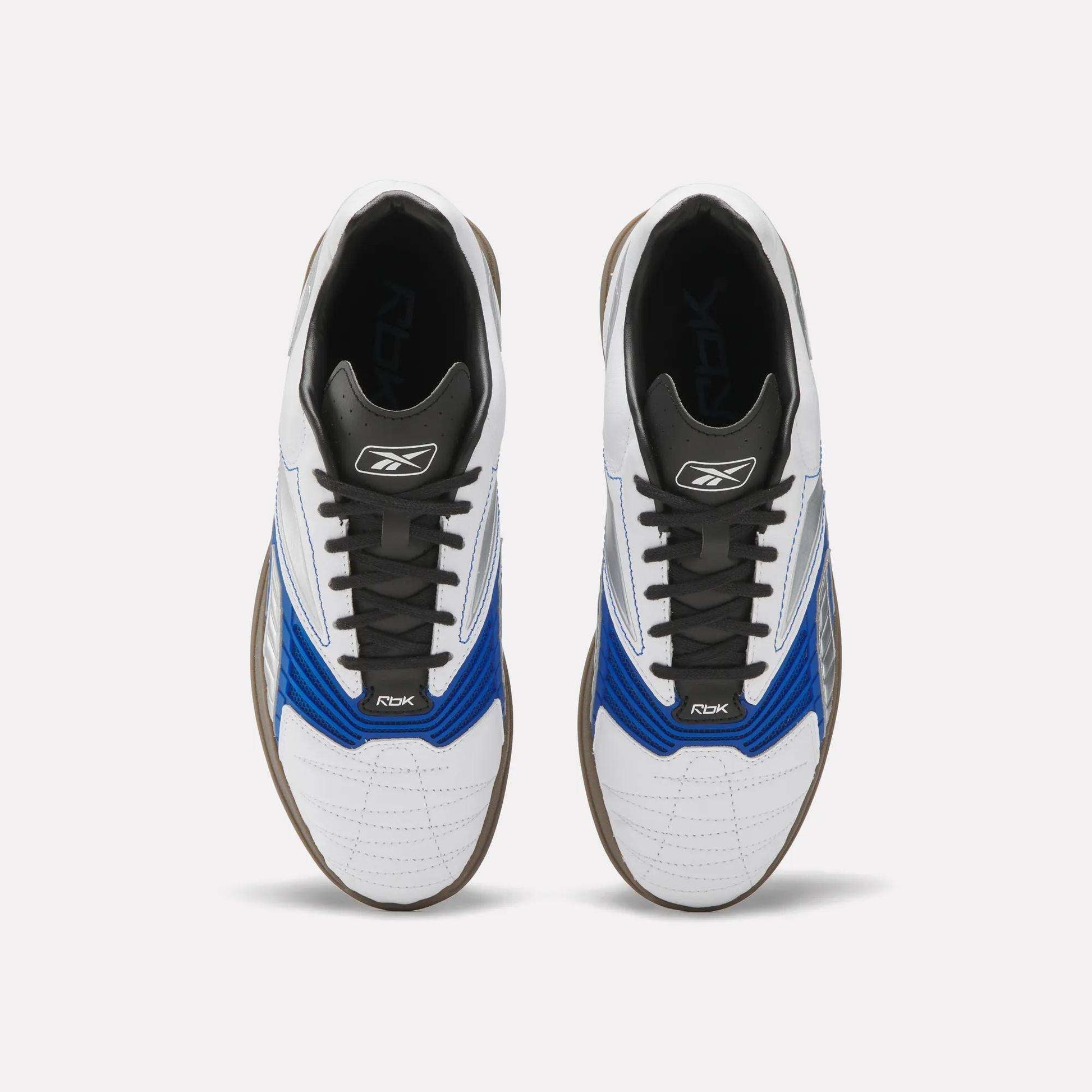 A pair of Reebok Hammer Valde Shoes seen from above, with a white leather upper, blue and black accents, black laces, brown soles, and branding on the tongue and side.