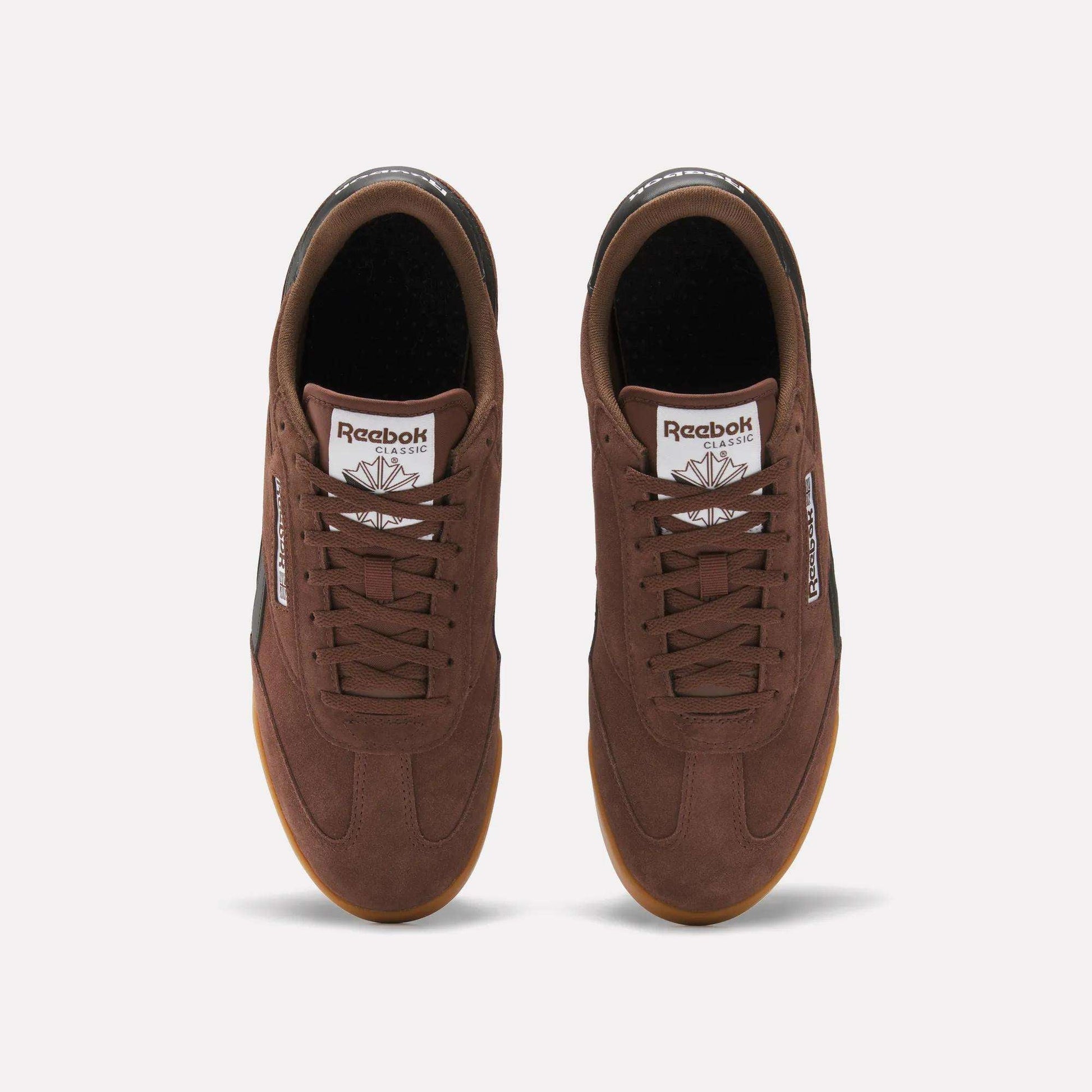 Top view of a pair of brown Reebok Campio XT Shoes with gum soles, brown laces, and white logos on the tongues and sides, inspired by '90s soccer style, shown on a plain white background.