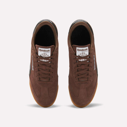 Top view of a pair of brown Reebok Campio XT Shoes with gum soles, brown laces, and white logos on the tongues and sides, inspired by '90s soccer style, shown on a plain white background.