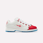 The Reebok Question Golf Shoes are premium white athletic sneakers with red accents including a red toe cap and logo, blue outsole, and white laces. Shown in a modern side view on a plain light background for a spikeless golf look.
