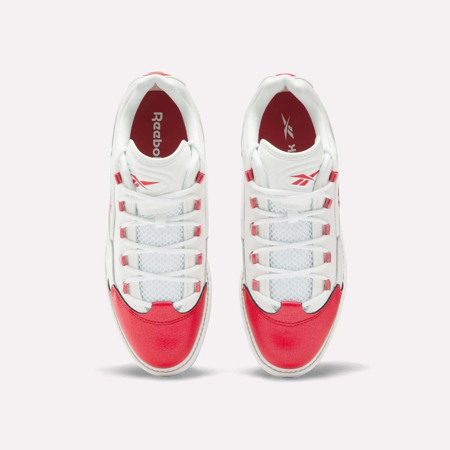 A pair of Reebok Question Golf Shoes viewed from above, showcasing white uppers with bright red accents on the toe, heel, and sides—these stylish spikeless shoes feature white laces threaded through red and white eyelets.