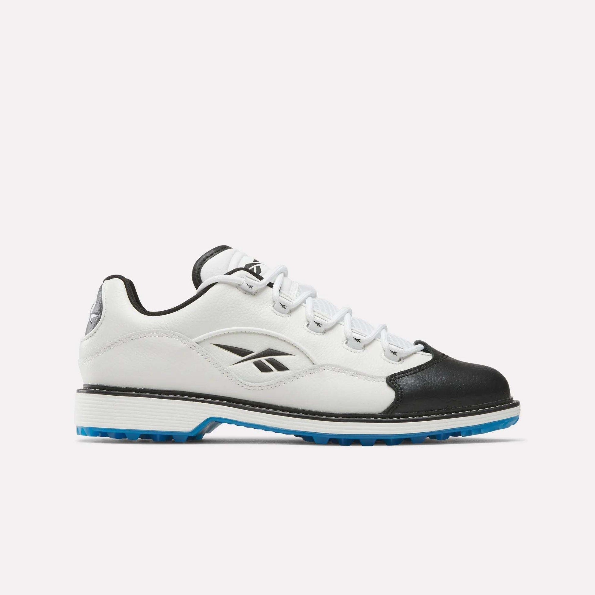The Reebok Question Golf Shoes feature a white and black low-top design with blue sole accents, crafted from full grain leather and adorned with the Reebok logo, highlighting premium style against a plain light background.