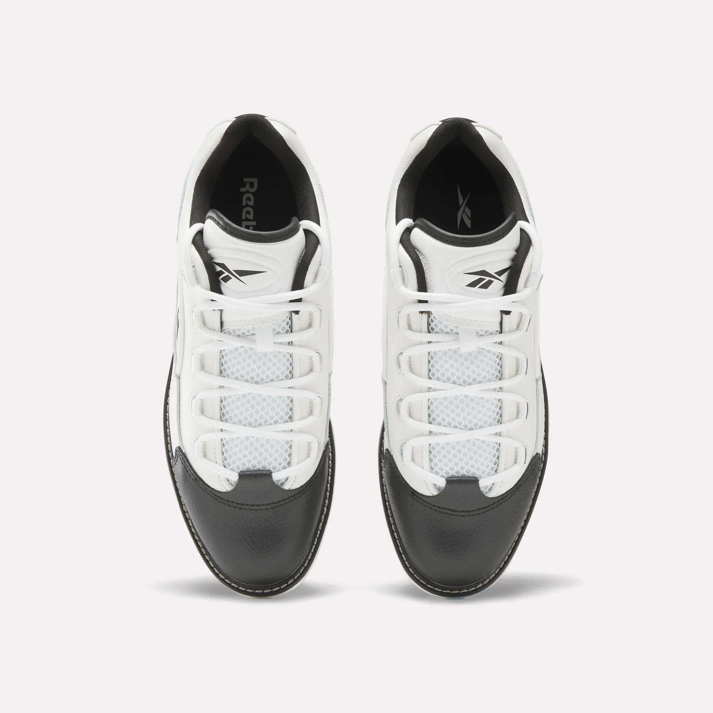 Top view of a pair of Reebok Question Golf Shoes in white and black, showcasing a premium design with white laces, black toe caps, and mesh detailing on the upper.