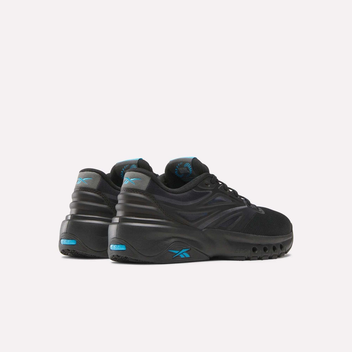 A pair of Reebok Men's ERS Training Shoes in black with blue accents and chunky soles, featuring premium cushioning. Displayed on a light background, the heels face forward and are slightly turned to the right.