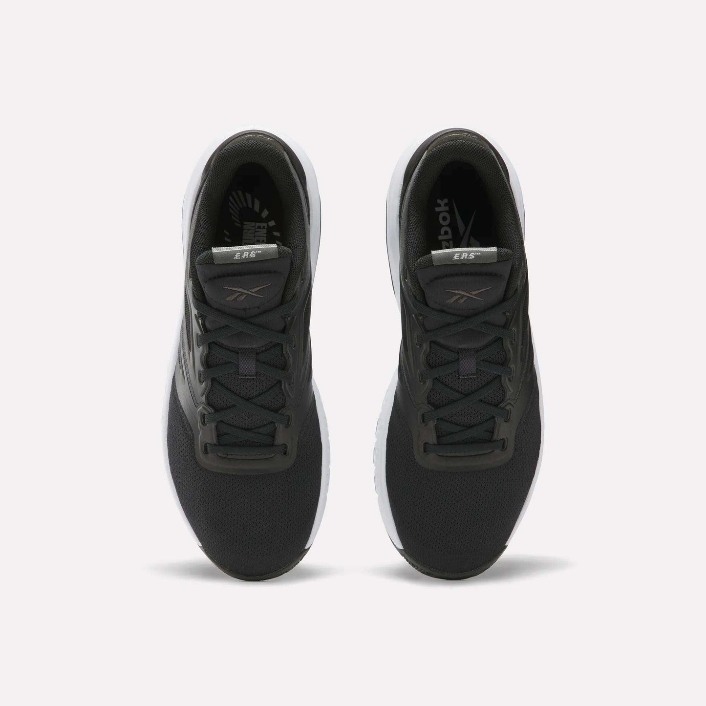 A pair of Reebok Men's ERS Training Shoes with black uppers, white soles, and gray accents on the tongue and sides are shown side by side on a plain white background, offering premium cushioning for comfort.