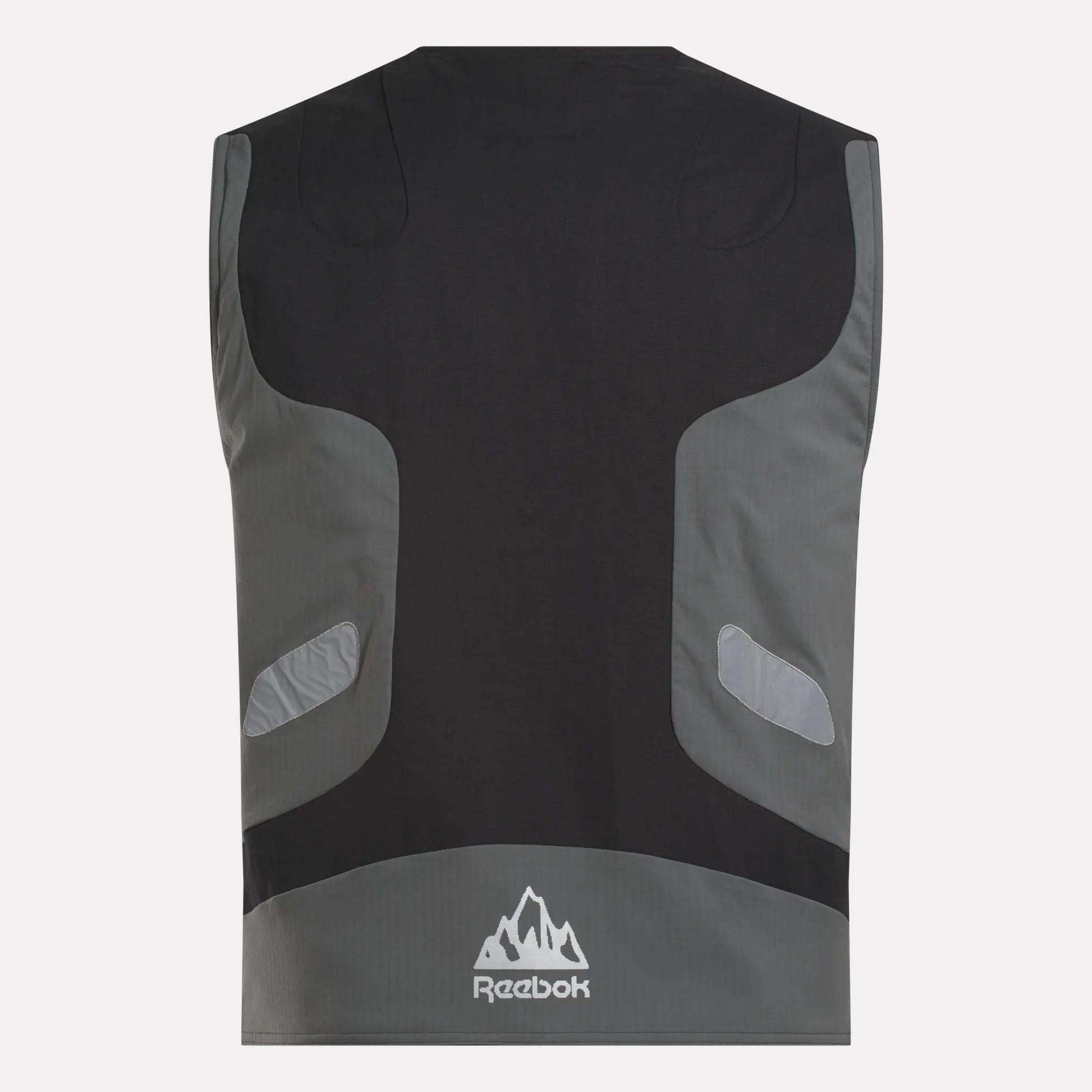 The Reebok x MARKET Reversible Vest is shown from the back in black and gray with reflective accents, a mountain-shaped Reebok logo near the hem, and a streetwear-inspired design.