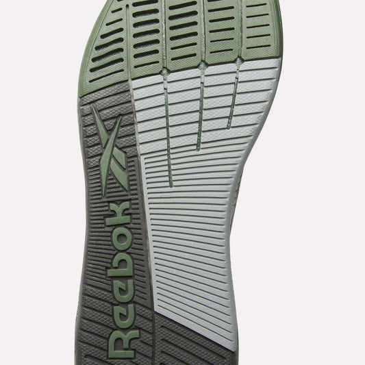 The image displays the sole of Reebok’s Nano X5 Training Shoes for men, boasting a mix of light green and gray, textured grip patterns, horizontal grooves, and the signature Reebok logo—ideal for stylish comfort during training.