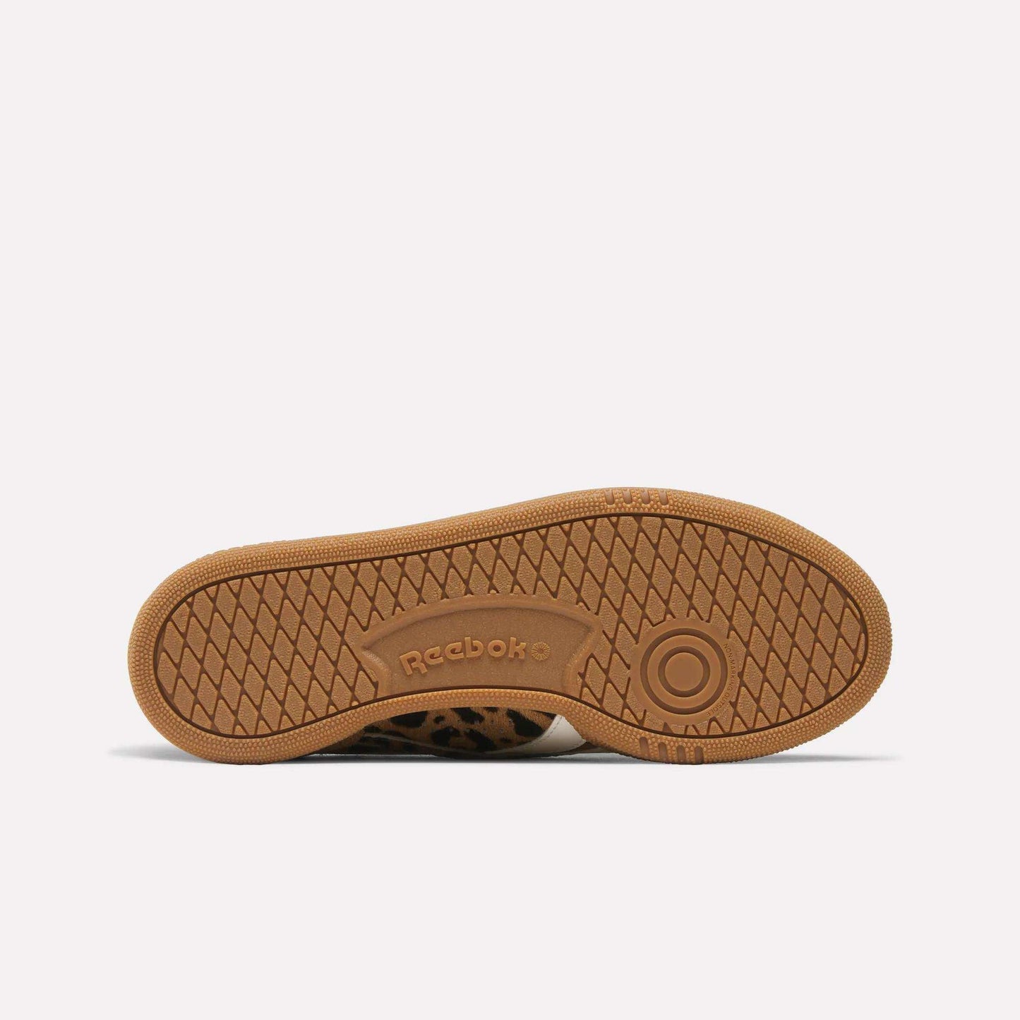The brown, textured rubber sole of the Reebok Women's Club C Grounds UK shoe features the Reebok logo and a circular grip pattern, displayed against a plain white background.