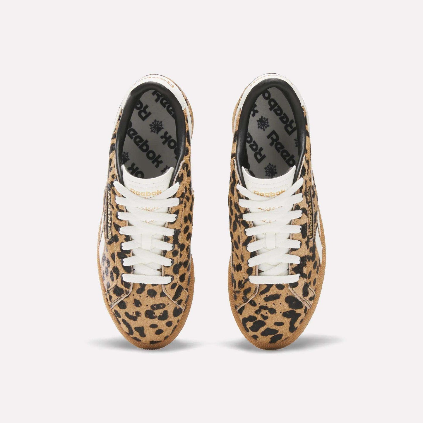 A pair of Reebok Women's Club C Grounds UK Shoes with a tan and black leopard print, white laces, and black Reebok insoles is seen from above on a plain white background.