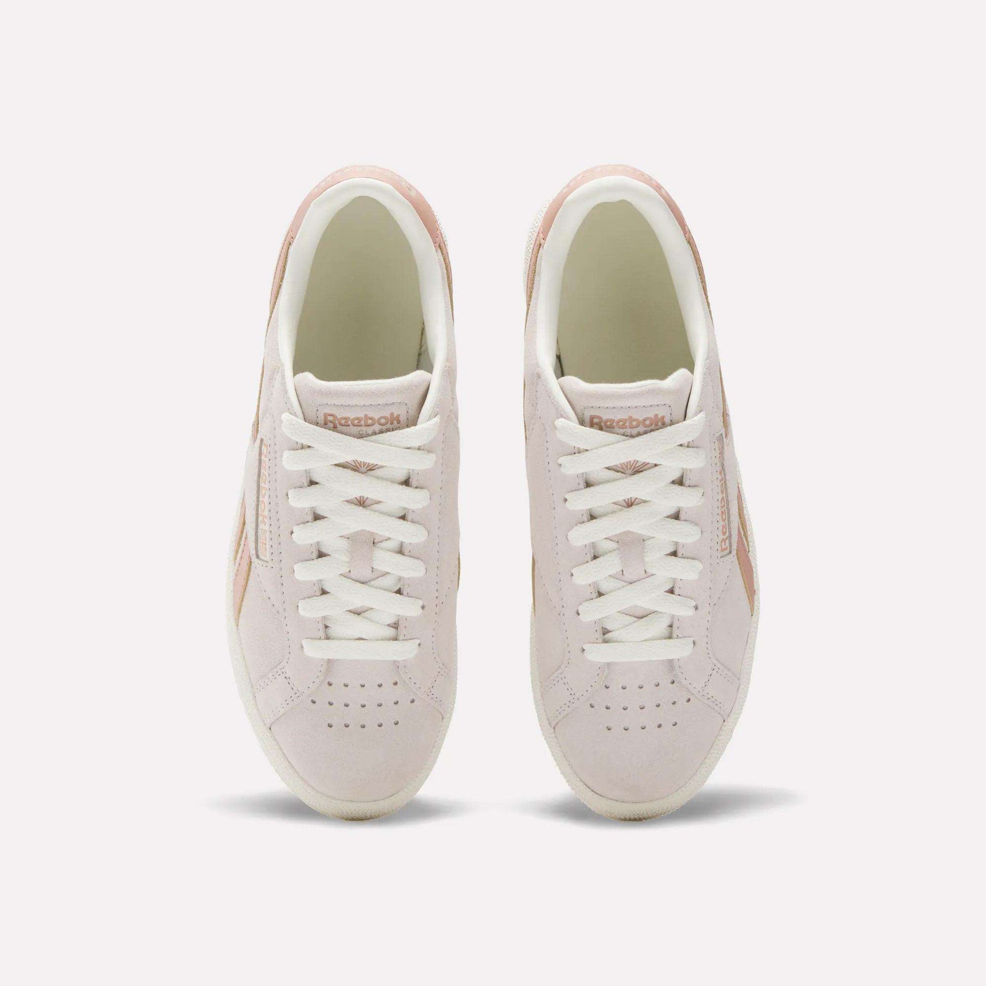 A top view of the Reebok Women's Club C Grounds UK Shoes in light pink, featuring white laces, beige details, suede and leather accents, and the Reebok logo on the tongue.