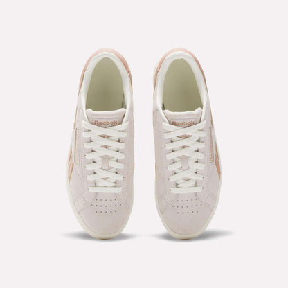 A top view of the Reebok Women's Club C Grounds UK Shoes in light pink, featuring white laces, beige details, suede and leather accents, and the Reebok logo on the tongue.