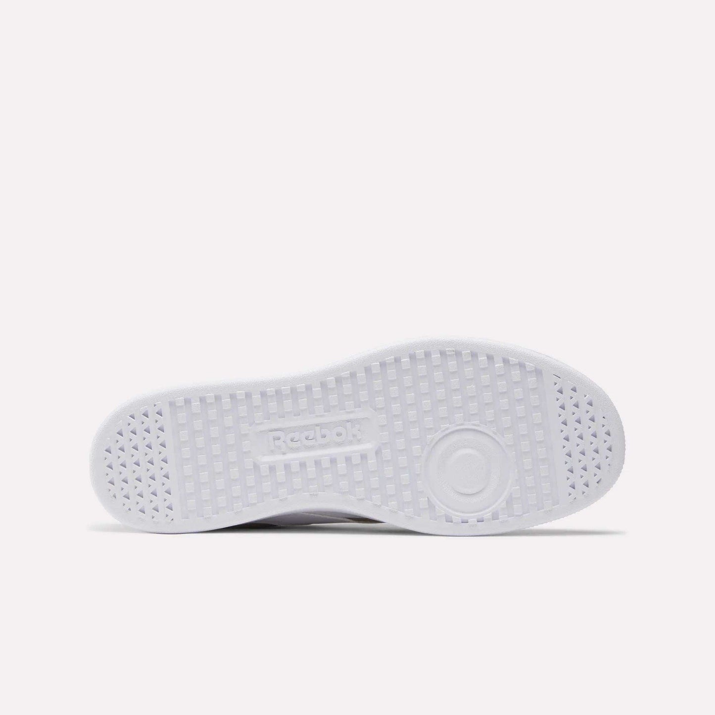 The image shows the white sole of Reebok Smash Edge Shoes lying flat, featuring a central Reebok logo and a textured grid outsole pattern for grip—ideal for indoor soccer surfaces.