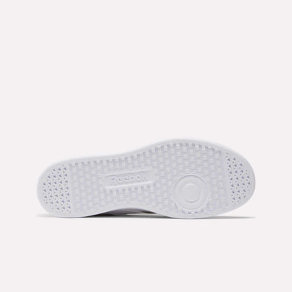 The image shows the white sole of Reebok Smash Edge Shoes lying flat, featuring a central Reebok logo and a textured grid outsole pattern for grip—ideal for indoor soccer surfaces.